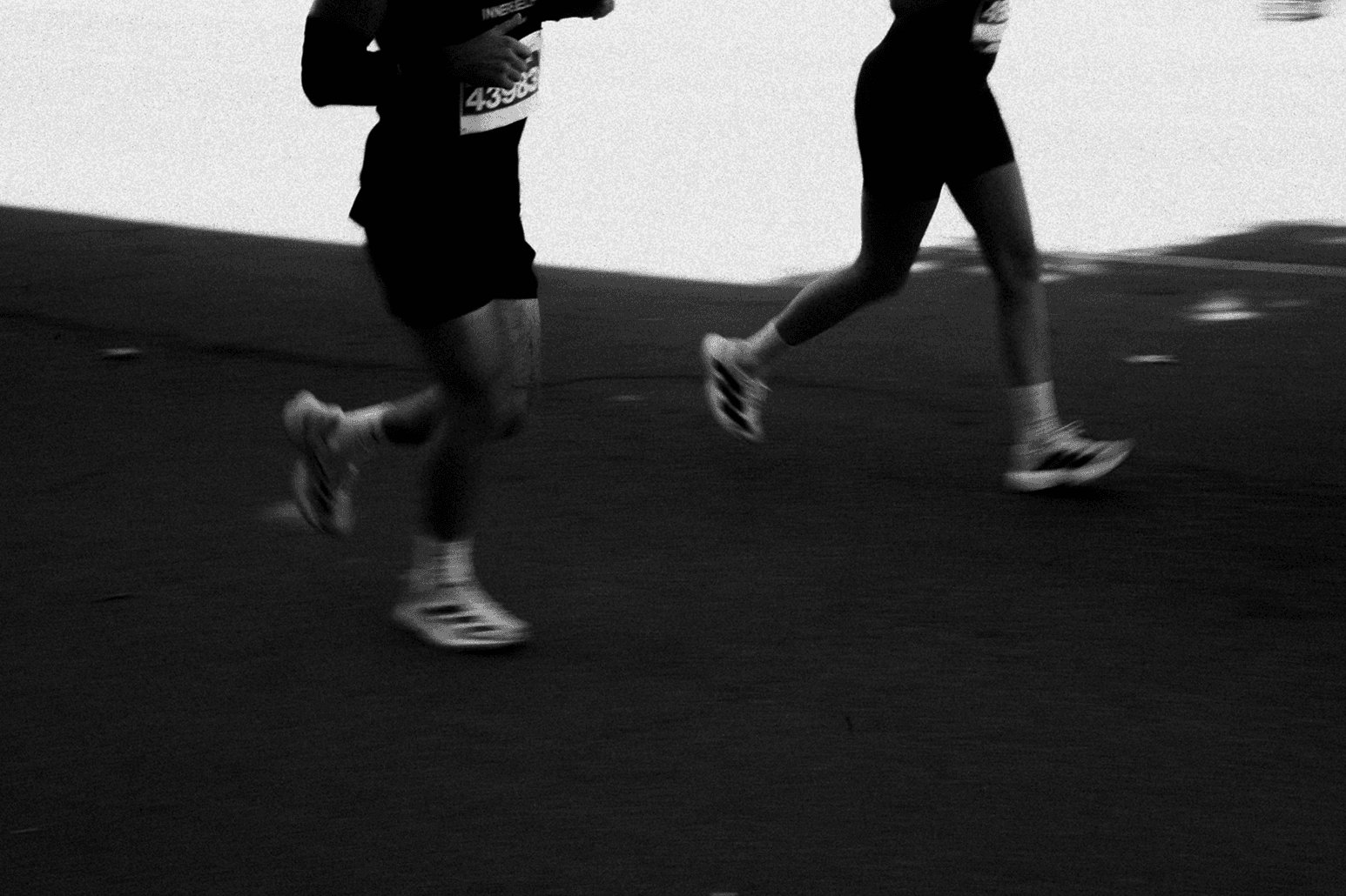 Two runners training on an open road, black and white motion shot